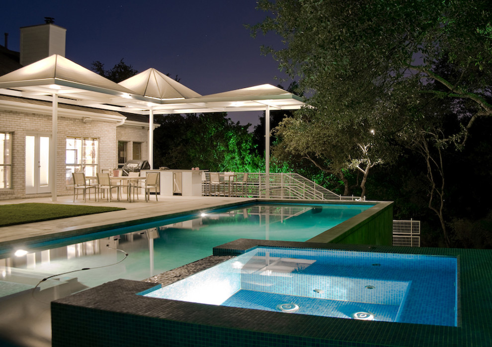 This is an example of a contemporary rectangular pool in Austin with concrete slab and a hot tub.
