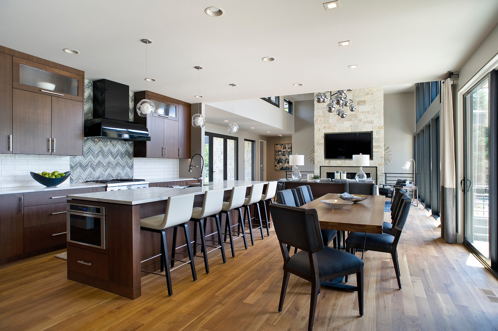 Example of a large transitional l-shaped medium tone wood floor and brown floor eat-in kitchen design with a farmhouse sink, flat-panel cabinets, dark wood cabinets, marble countertops, white backsplash, subway tile backsplash, paneled appliances and an island