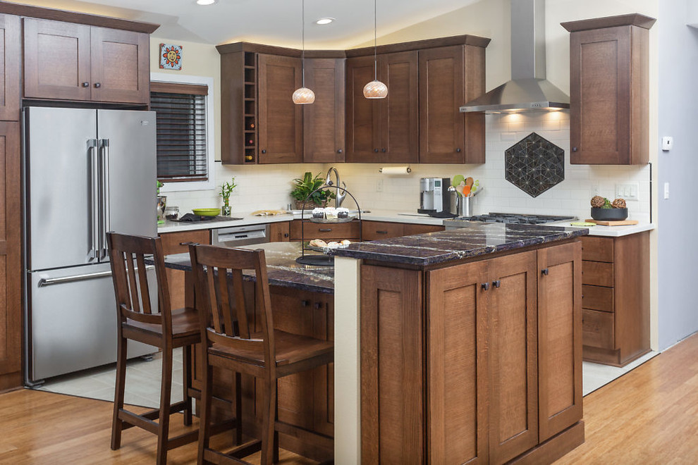 Example of a mid-sized transitional l-shaped open concept kitchen design with recessed-panel cabinets, dark wood cabinets, quartz countertops, white backsplash, subway tile backsplash, stainless steel appliances and an island