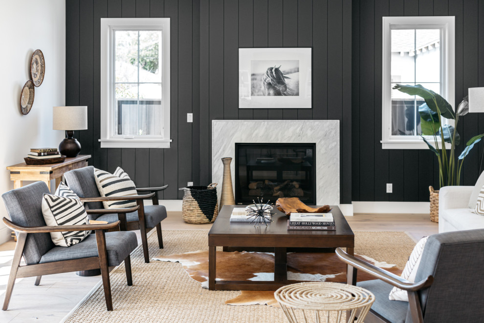 Photo of a country family room in Los Angeles with black walls, light hardwood floors, a standard fireplace, a stone fireplace surround, beige floor and planked wall panelling.