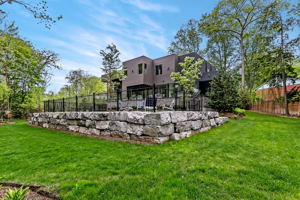 Photo of a large transitional partial sun backyard stone formal garden in Toronto with a fire pit.