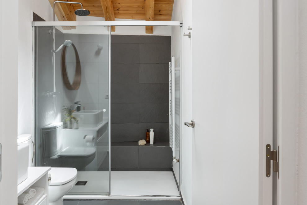 Пример оригинального дизайна: большой туалет в стиле модернизм с открытыми фасадами, белыми фасадами, унитазом-моноблоком, серой плиткой, серыми стенами, паркетным полом среднего тона, раковиной с несколькими смесителями, столешницей из плитки, коричневым полом, серой столешницей, встроенной тумбой и балками на потолке