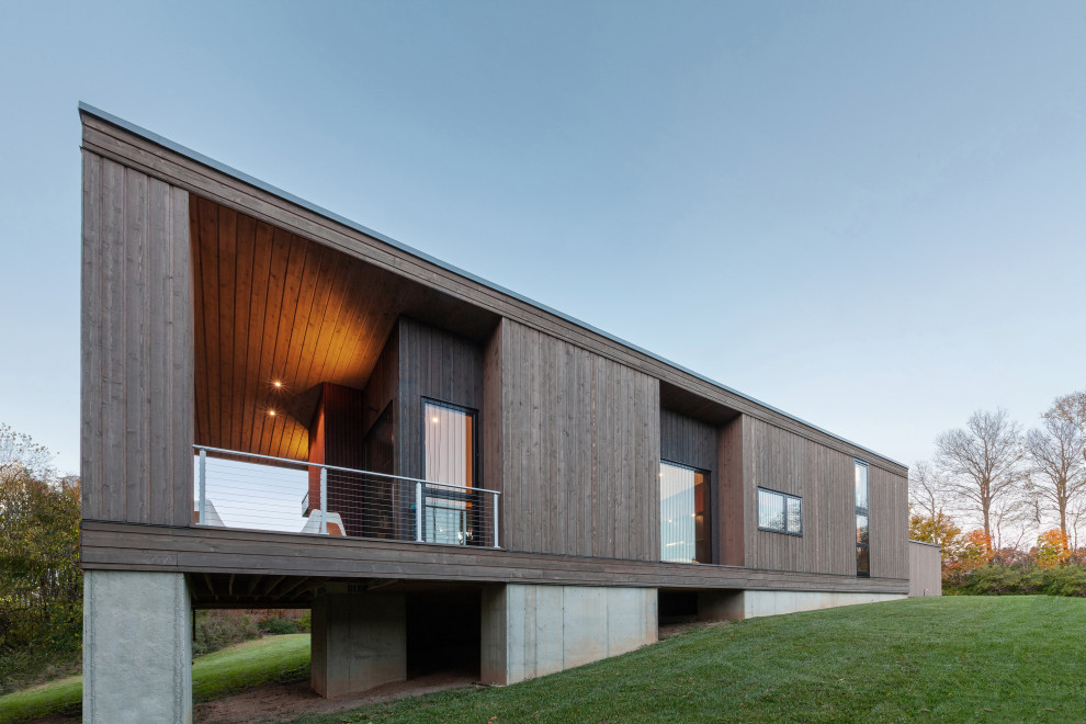 Idee per la facciata di una casa piccola grigia moderna a un piano con rivestimento in legno, copertura in metallo o lamiera, tetto grigio e terreno in pendenza
