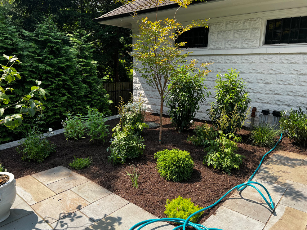 Photo of a large mediterranean back full sun garden in New York with a flowerbed, natural stone paving and a metal fence.