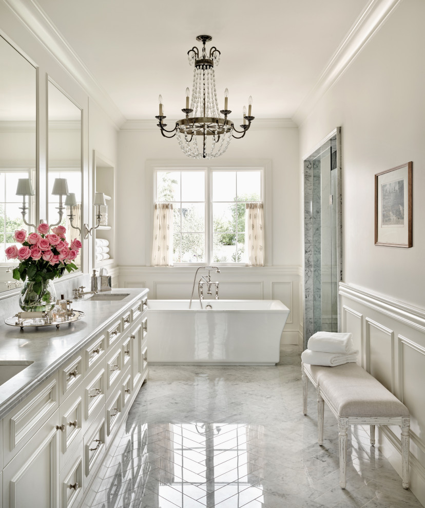 Inspiration for a large mediterranean master bathroom in Phoenix with a freestanding tub, marble floors, recessed-panel cabinets, white cabinets, white walls, an undermount sink, grey floor, grey benchtops, a double vanity, a built-in vanity and decorative wall panelling.