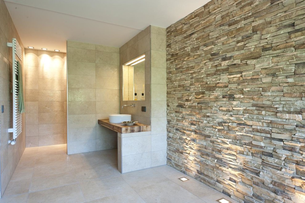 This is an example of a mid-sized contemporary 3/4 bathroom in Other with beige tile, stone tile, grey walls, a vessel sink, a curbless shower, limestone floors, wood benchtops and brown benchtops.