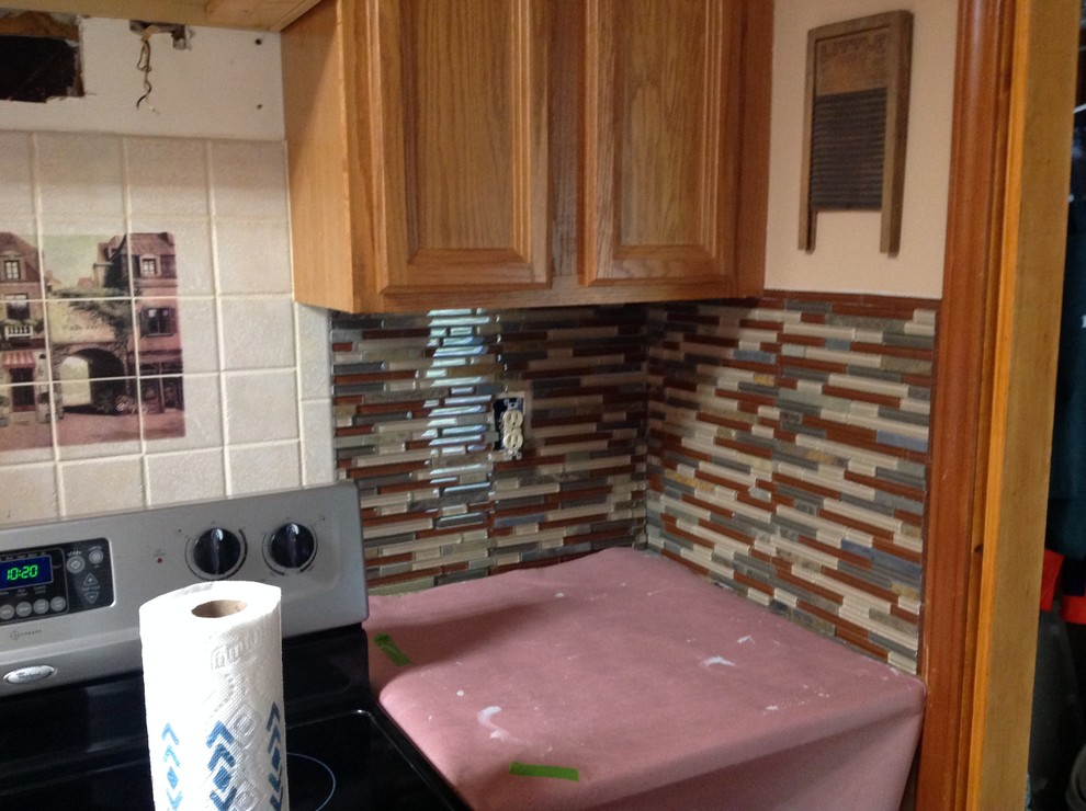 Inspiration for a l-shaped eat-in kitchen remodel with an undermount sink, flat-panel cabinets, brown backsplash, glass tile backsplash, stainless steel appliances and a peninsula
