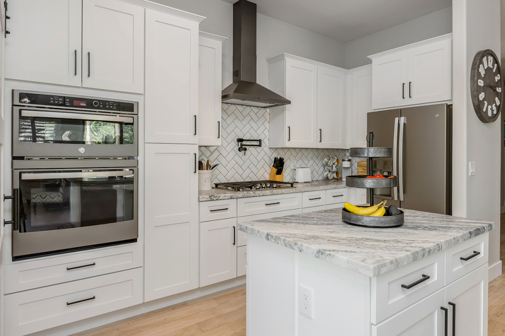 Mid-sized transitional single-wall eat-in kitchen in Phoenix with an undermount sink, shaker cabinets, white cabinets, granite benchtops, white splashback, ceramic splashback, stainless steel appliances, porcelain floors, multiple islands, brown floor and white benchtop.