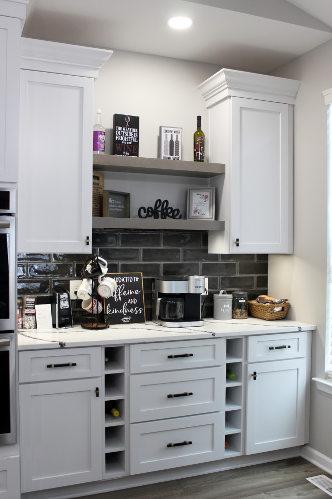 Eat-in kitchen - large transitional single-wall vinyl floor and beige floor eat-in kitchen idea with a farmhouse sink, shaker cabinets, white cabinets, quartz countertops, black backsplash, subway tile backsplash, stainless steel appliances, an island and white countertops