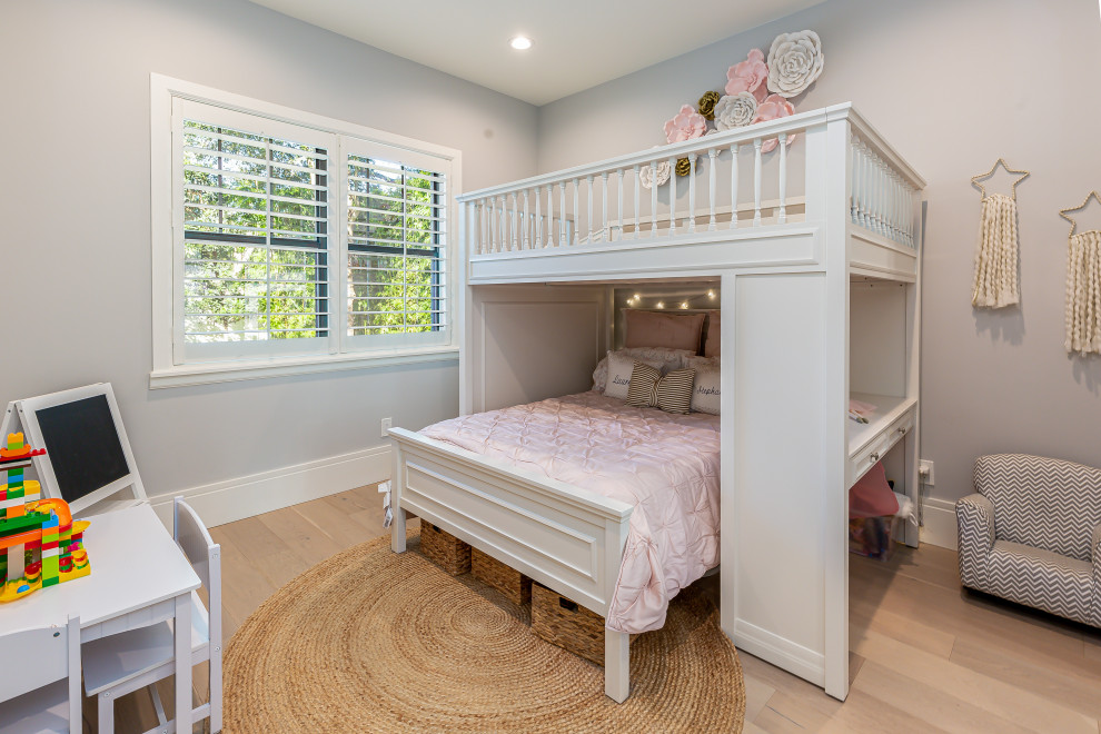 Modelo de habitación de bebé tradicional renovada de tamaño medio con paredes grises, suelo de madera clara y suelo blanco