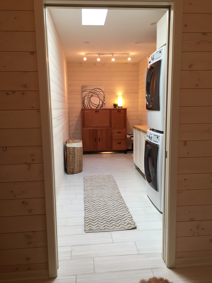 Photo of a scandinavian laundry room in Minneapolis with porcelain floors and a stacked washer and dryer.