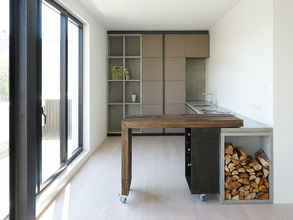 This is an example of a small contemporary l-shaped separate kitchen in Berlin with an undermount sink, flat-panel cabinets, brown cabinets, concrete benchtops, white splashback, panelled appliances, with island, light hardwood floors and beige floor.
