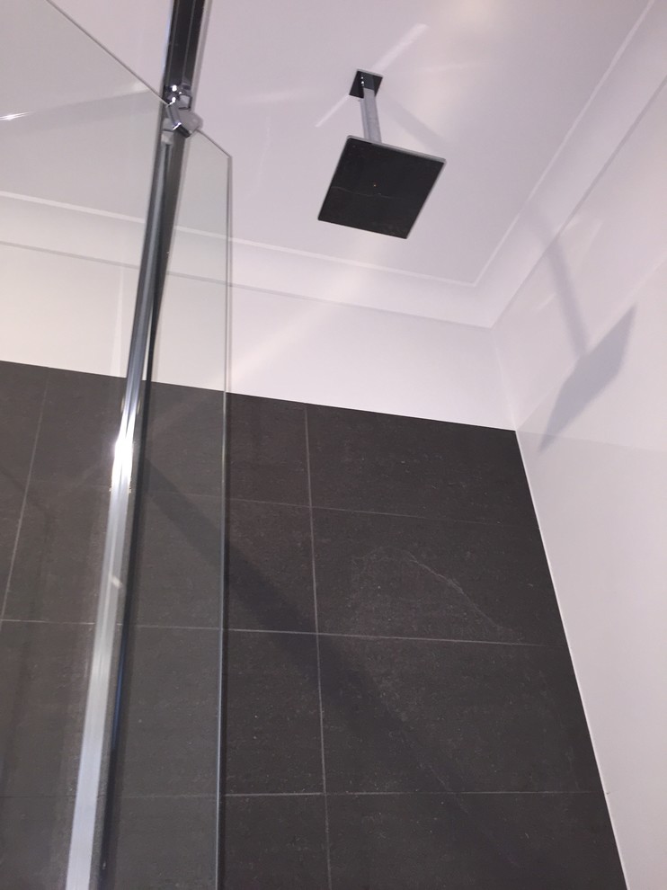 This is an example of a mid-sized contemporary bathroom in Sydney with white cabinets, a drop-in tub, porcelain tile, white walls and porcelain floors.