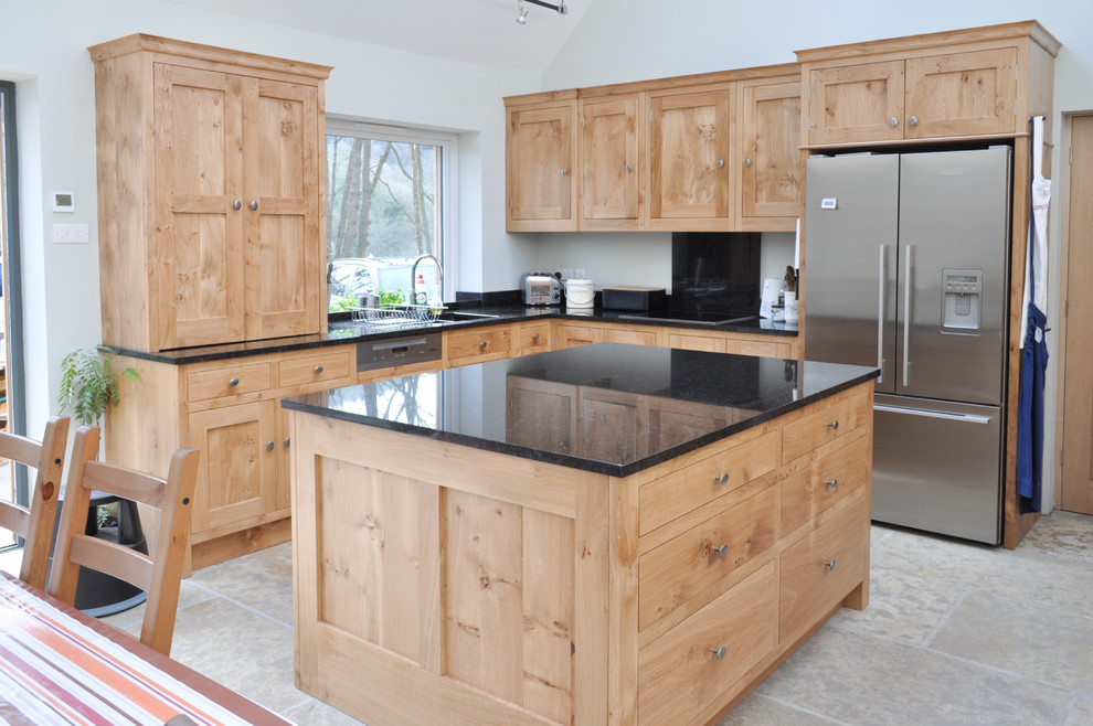 Design ideas for a large traditional l-shaped eat-in kitchen in Other with an undermount sink, shaker cabinets, light wood cabinets, granite benchtops, black splashback, stone slab splashback, stainless steel appliances, limestone floors and with island.