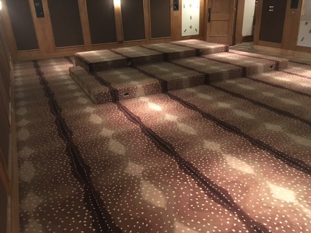 This is an example of a large traditional enclosed home theatre in Chicago with brown walls, carpet, brown floor and a wall-mounted tv.