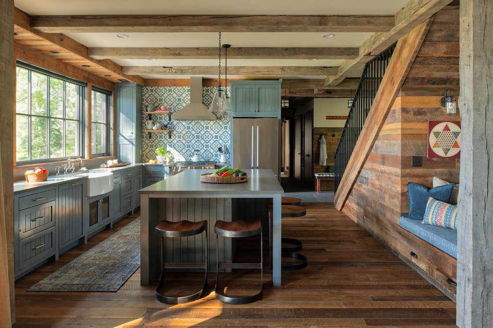 Country l-shaped kitchen in Minneapolis with a farmhouse sink, shaker cabinets, blue cabinets, multi-coloured splashback, stainless steel appliances, dark hardwood floors, with island, brown floor and grey benchtop.