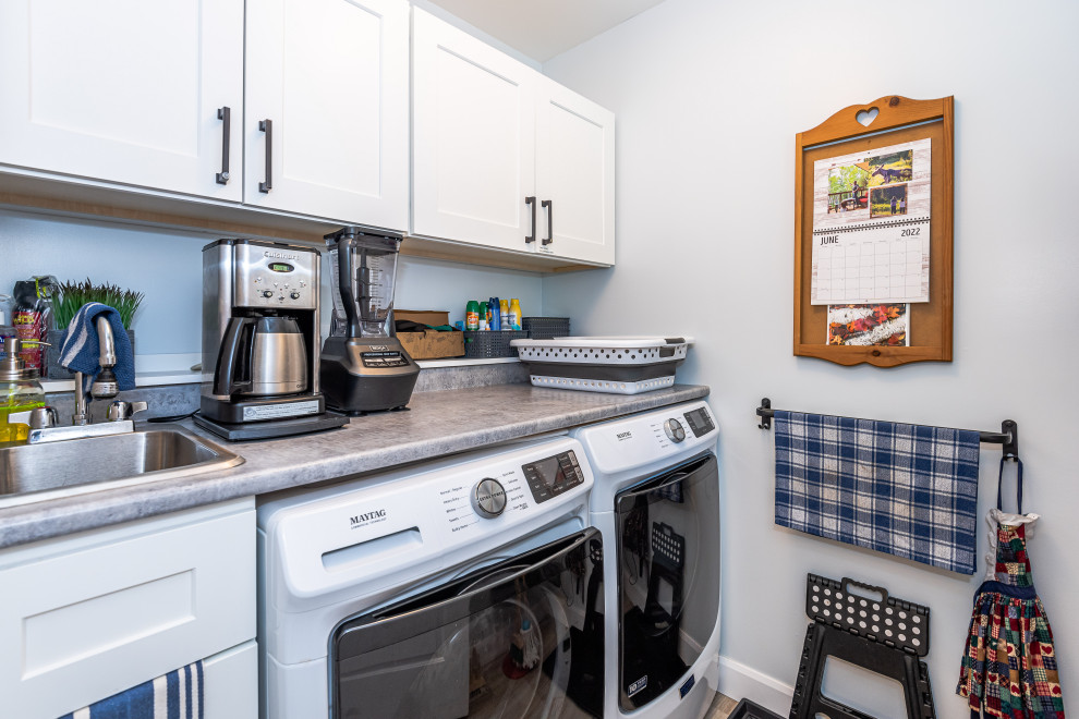 トロントにある高級な中くらいなラスティックスタイルのおしゃれな洗濯室 (シングルシンク、白いキャビネット、青い壁、ラミネートの床、左右配置の洗濯機・乾燥機、茶色い床、グレーのキッチンカウンター) の写真
