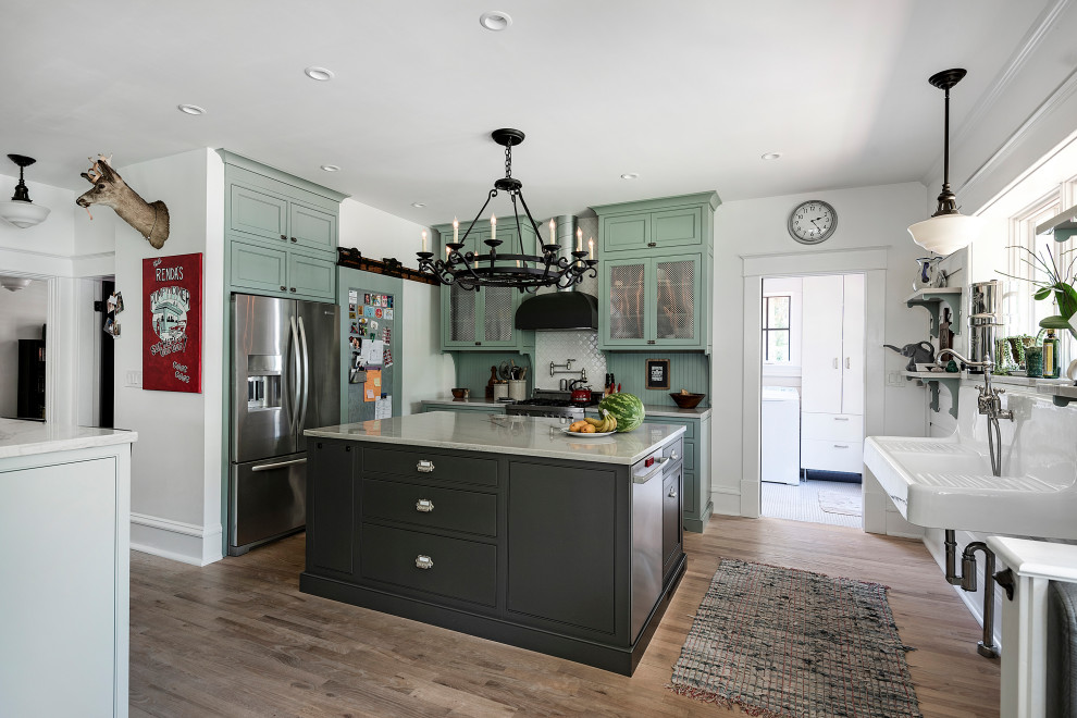 Large country l-shaped eat-in kitchen in Jacksonville with a farmhouse sink, shaker cabinets, green cabinets, stainless steel appliances, medium hardwood floors and multiple islands.