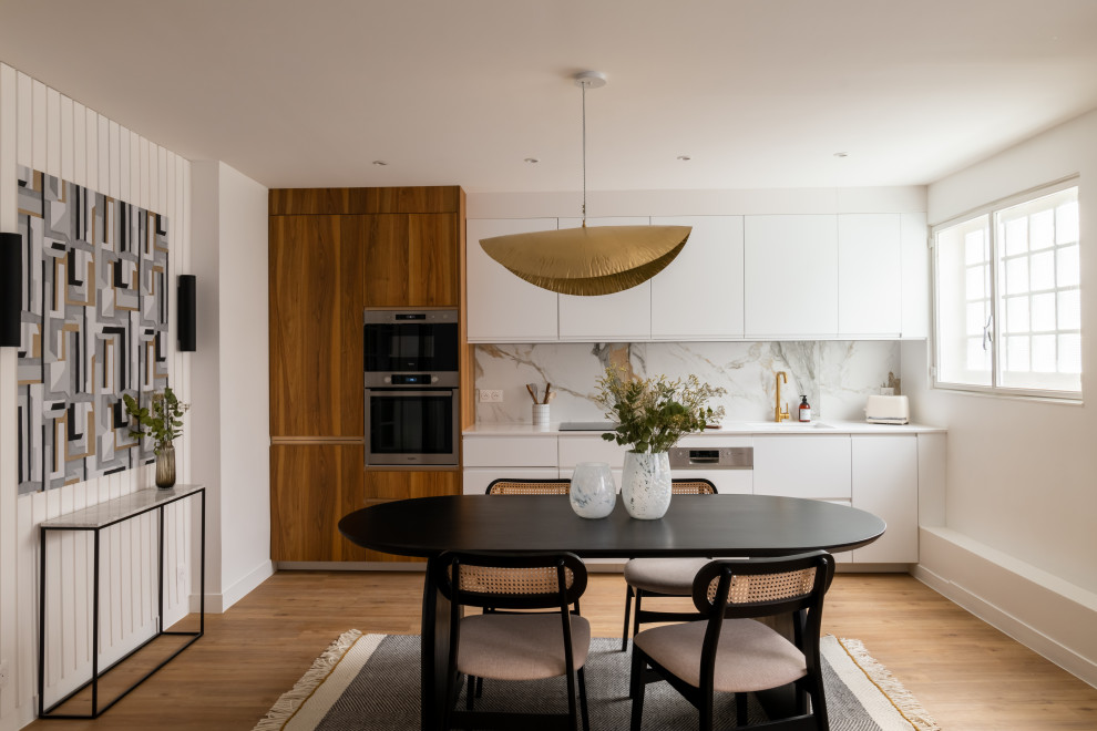 Large contemporary single-wall open plan kitchen in Paris with white cabinets, quartzite benchtops, multi-coloured splashback, light hardwood floors, brown floor and white benchtop.