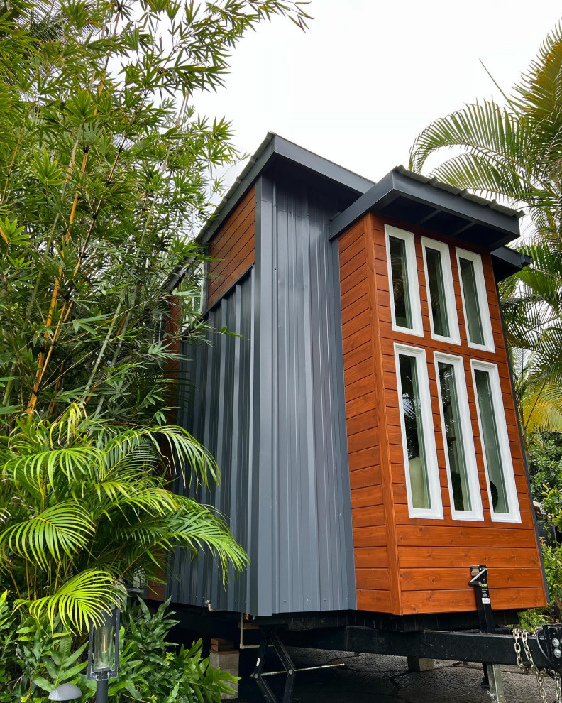 Foto della facciata di una casa piccola grigia contemporanea a due piani con rivestimento in metallo, copertura in metallo o lamiera e tetto grigio