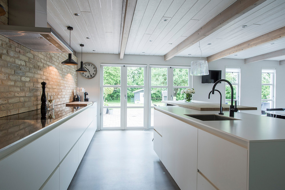Inspiration for a large contemporary galley open plan kitchen in Esbjerg with an undermount sink, flat-panel cabinets, white cabinets, stainless steel benchtops, concrete floors, with island and grey floor.