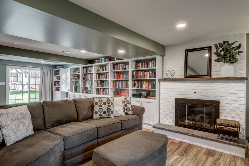 Example of a large arts and crafts walk-out vinyl floor and brown floor basement design in Other with green walls, a standard fireplace and a brick fireplace
