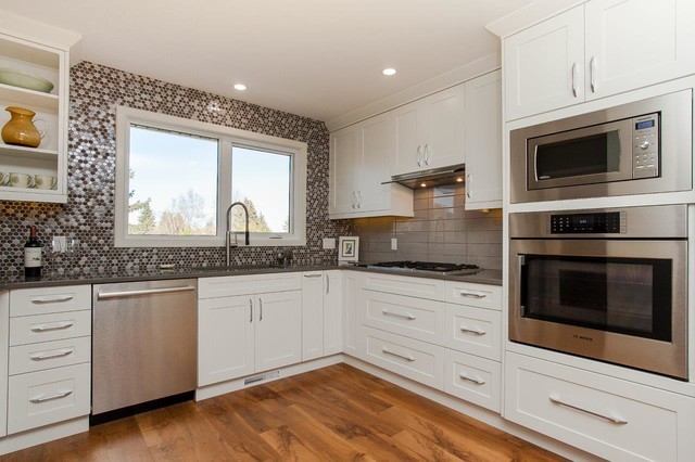 Example of a transitional u-shaped enclosed kitchen design in Edmonton with an undermount sink, shaker cabinets, white cabinets, concrete countertops, multicolored backsplash, mosaic tile backsplash, stainless steel appliances and no island