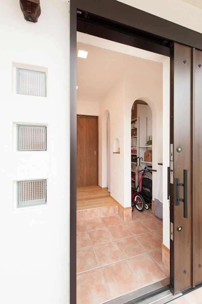 Entryway in Other with white walls, terra-cotta floors, a sliding front door, a dark wood front door and beige floor.