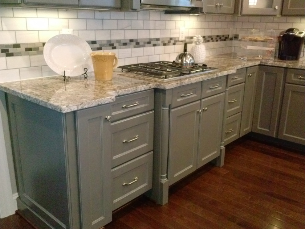 Inspiration for a mid-sized transitional l-shaped medium tone wood floor and red floor eat-in kitchen remodel with an undermount sink, raised-panel cabinets, gray cabinets, granite countertops, multicolored backsplash, subway tile backsplash, stainless steel appliances, an island and multicolored countertops