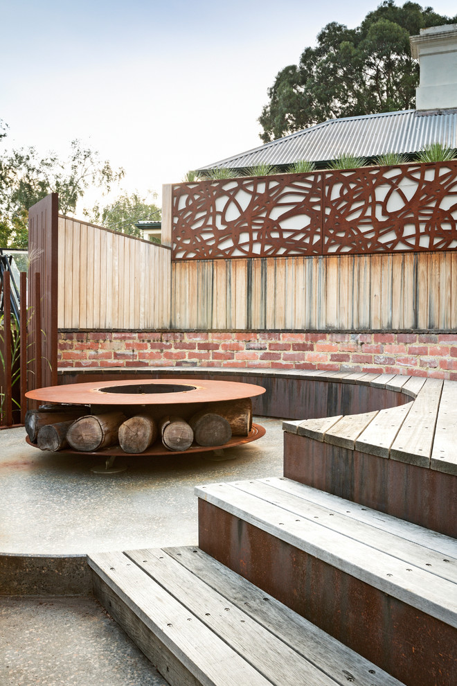 Modern side yard deck in Melbourne with a fire feature and no cover.