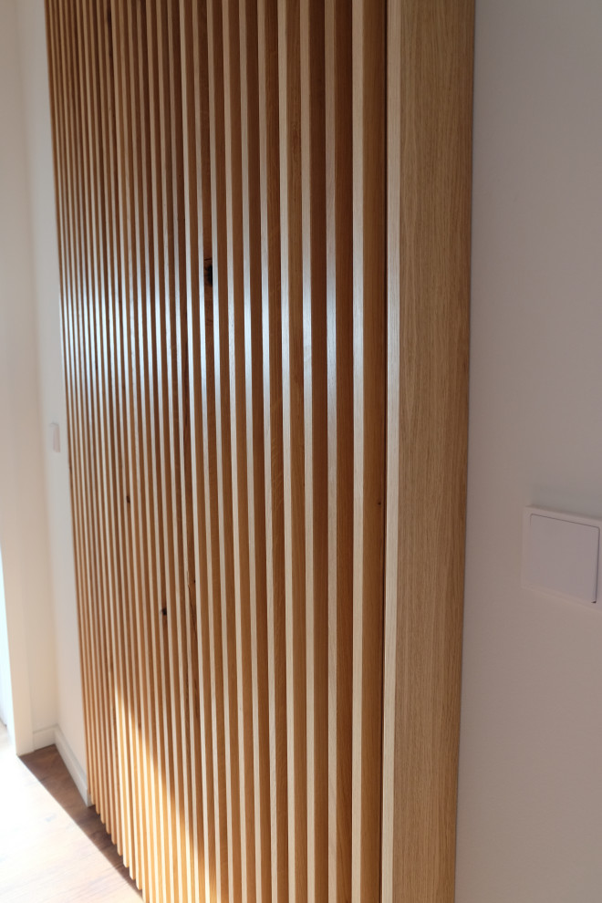 На фото: большой коридор в современном стиле с белыми стенами, полом из ламината, коричневым полом и деревянными стенами с