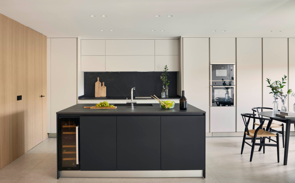 Ejemplo de cocina gris y negra moderna grande con armarios con paneles empotrados, puertas de armario blancas, suelo de cemento, una isla, suelo gris y microcemento
