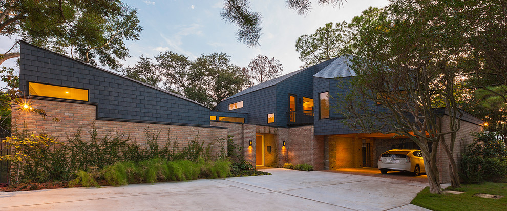This is an example of a large contemporary two-storey brick red house exterior in Houston with a hip roof and a shingle roof.