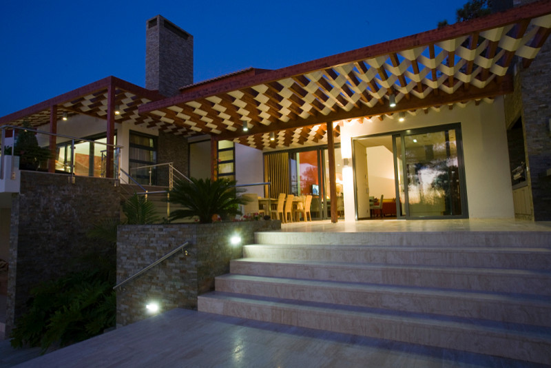 Example of a mid-sized transitional backyard stone home design design with a fire pit and a pergola