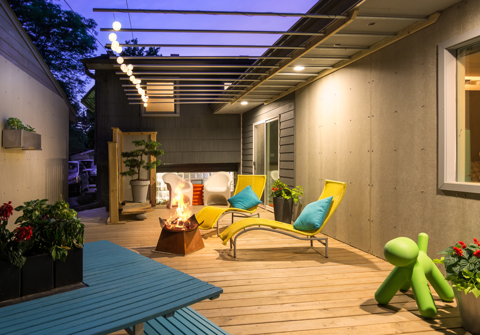 Mid-sized modern backyard deck in Detroit with a fire feature and a roof extension.