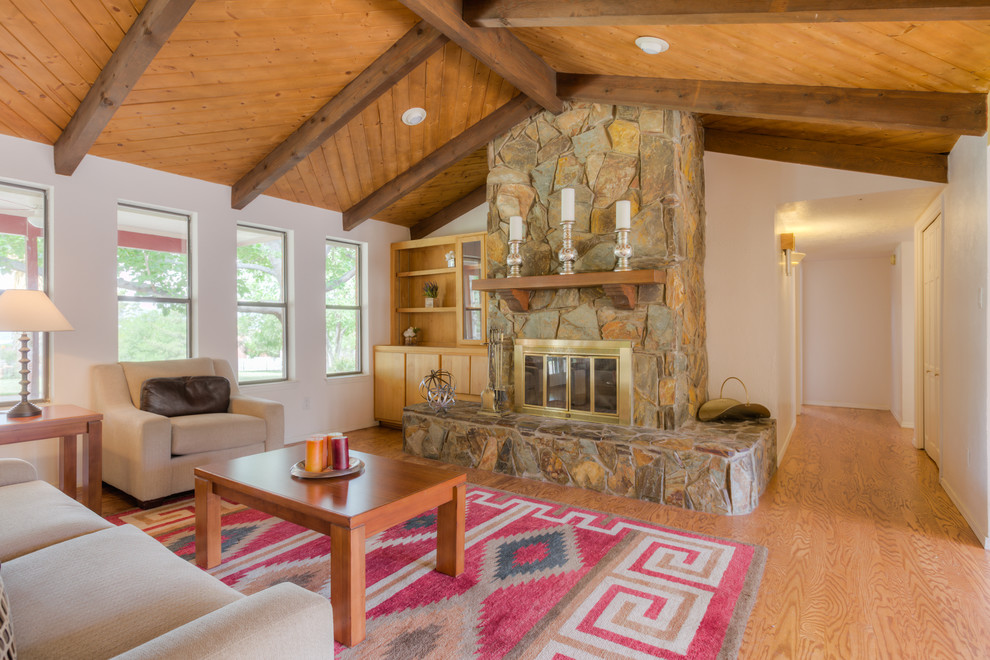 Expansive traditional formal open concept living room in Albuquerque with yellow walls, medium hardwood floors, a standard fireplace and a stone fireplace surround.