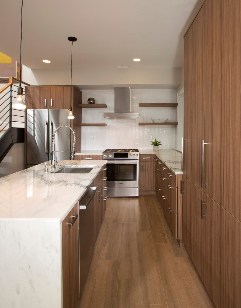 This is an example of a mid-sized contemporary l-shaped eat-in kitchen in DC Metro with white splashback, ceramic splashback, an undermount sink, flat-panel cabinets, medium wood cabinets, marble benchtops, stainless steel appliances, medium hardwood floors and with island.