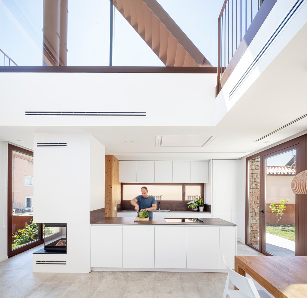 This is an example of a mid-sized contemporary l-shaped eat-in kitchen in Other with an integrated sink, flat-panel cabinets, white cabinets, quartz benchtops, metallic splashback, white appliances, ceramic floors, with island, beige floor and brown benchtop.