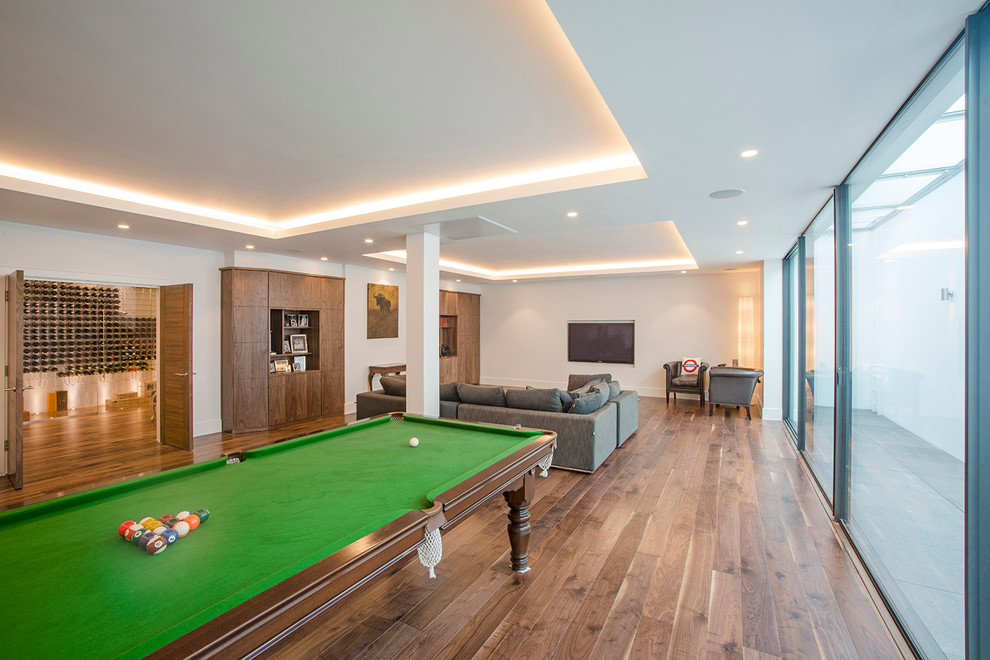 Photo of a large contemporary open concept family room in London with medium hardwood floors, a wall-mounted tv and white walls.