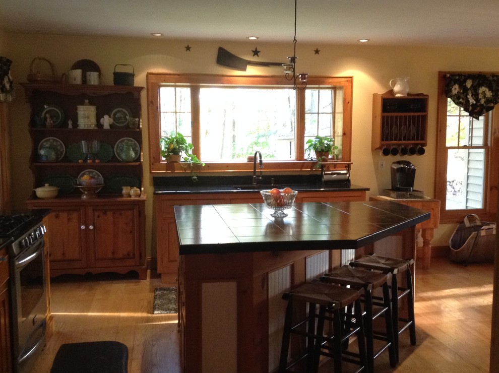 Photo of a large country eat-in kitchen in New York with an undermount sink, stainless steel appliances, light hardwood floors and with island.