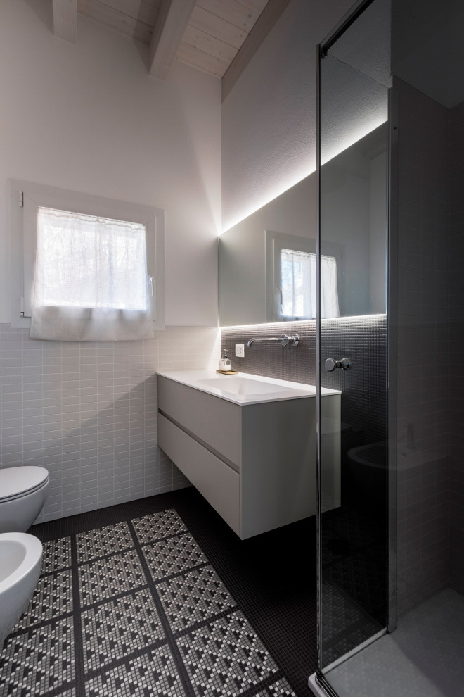 Idéer för små funkis vitt badrum med dusch, med släta luckor, gröna skåp, en hörndusch, en vägghängd toalettstol, vit kakel, mosaik, vita väggar, mosaikgolv, ett väggmonterat handfat, bänkskiva i akrylsten, flerfärgat golv och dusch med gångjärnsdörr