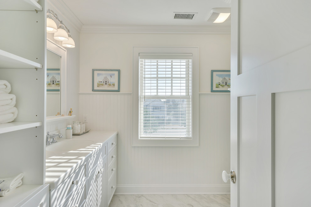 Design ideas for a beach style bathroom in Philadelphia with recessed-panel cabinets, white cabinets, a corner shower, white tile, subway tile, white walls, marble floors and an integrated sink.