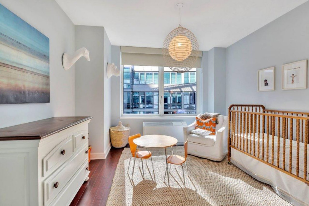 Idée de décoration pour une chambre de bébé design avec un mur gris et un sol en bois brun.