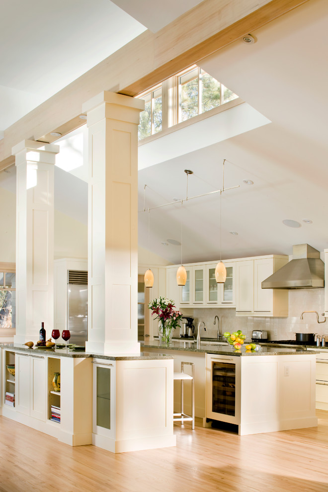 Photo of an expansive transitional u-shaped eat-in kitchen in Denver with shaker cabinets, white cabinets, stainless steel appliances, light hardwood floors and multiple islands.