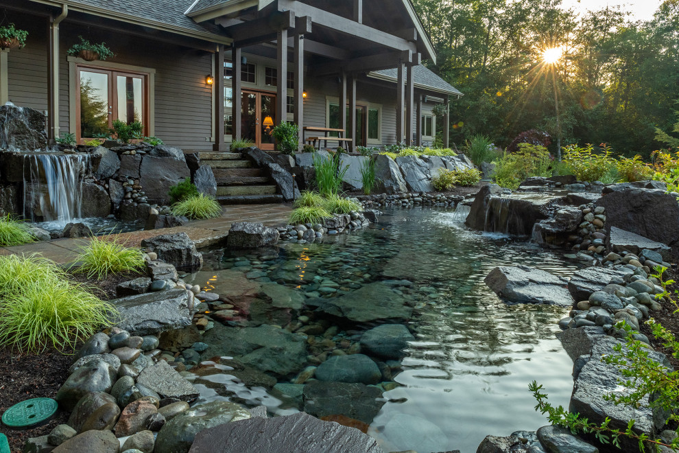 Ispirazione per un ampio giardino american style dietro casa con una cascata e pavimentazioni in pietra naturale