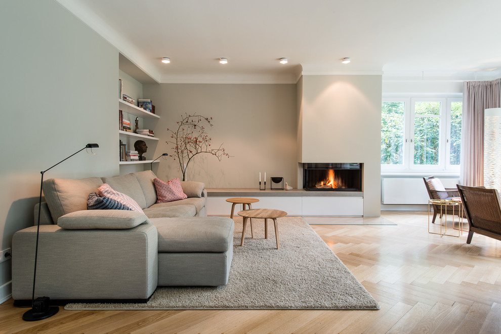 Inspiration for a large scandinavian open concept living room in Hamburg with beige walls, light hardwood floors, a ribbon fireplace and a plaster fireplace surround.