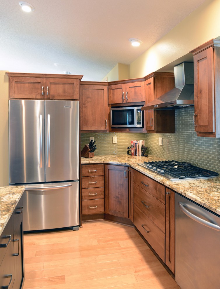 Example of a mid-sized transitional u-shaped light wood floor open concept kitchen design with an undermount sink, shaker cabinets, medium tone wood cabinets, granite countertops, glass tile backsplash, stainless steel appliances and an island