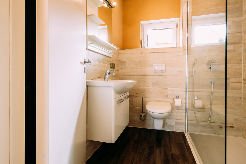 Small contemporary 3/4 wet room bathroom in Other with flat-panel cabinets, white cabinets, a two-piece toilet, beige tile, orange walls, medium hardwood floors, a vessel sink, brown floor and a hinged shower door.