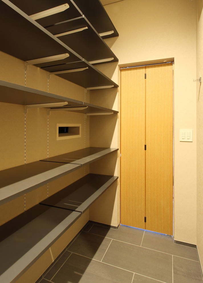 Diseño de armario vestidor unisex pequeño con armarios abiertos, puertas de armario grises, suelo de baldosas de porcelana y suelo gris