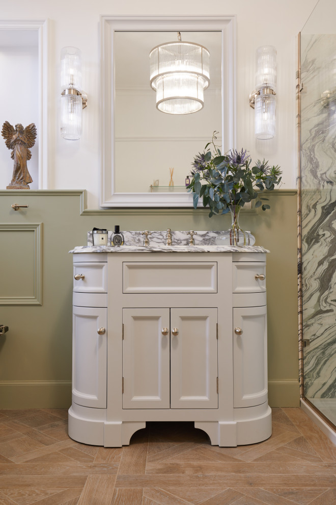 This is an example of a mid-sized contemporary kids bathroom in Other with a freestanding tub, an open shower, a one-piece toilet, green walls, light hardwood floors, a drop-in sink, marble benchtops, a hinged shower door, white benchtops, a niche and a freestanding vanity.